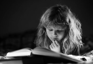 Çocuk kitabı okuyor. Küçük çocuk oturma odasında kitap okudu hikaye kitabındaki resimleri izledi. İlkokul için ödev yapan bir çocuk. Hayal gücü ya da öğrenme kavramı