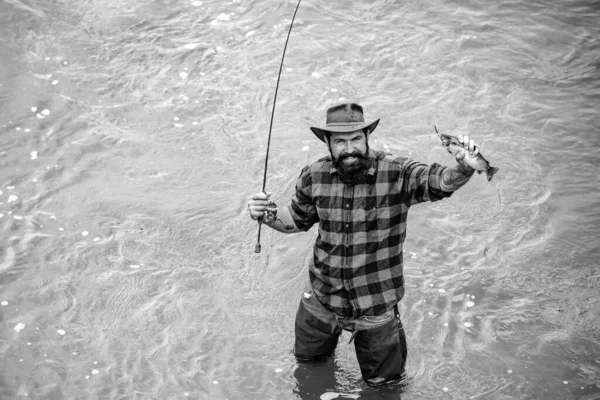 フィッシャーは魚と長い棒を持っている 男はリラックスして川で釣り 水の中で幸せなひげを生やした魚 楽しい時間を過ごす 晴れた日に活躍 趣味やスポーツ活動 男性趣味 — ストック写真