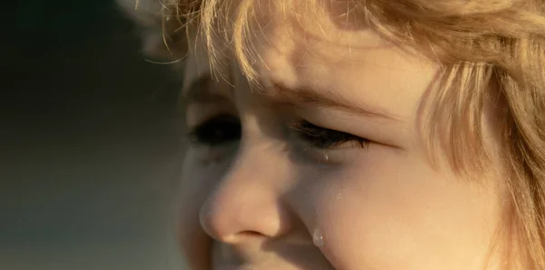 Closeup face of child boy crying outdoor. Tears on kids face closeup