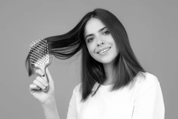 Beautiful woman combs her healthy hair. Combing healthy long straight female hair, close up