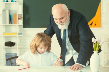 Öğrenci çocuk sınıfta öğreniyor. Öğretmen öğrenmeye yardımcı olur. Eğitim, öğretmenlik. Öğrenci çocuk dersi.