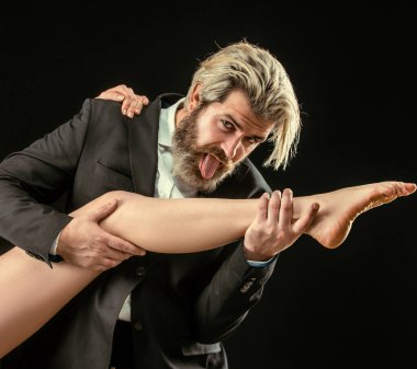 Ayak fetişisti. Lüks ve ataerkil düzen. Seksi kadın bacaklı, takım elbiseli yakışıklı işgüzar adam.