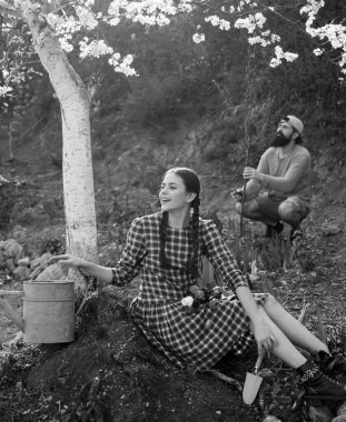 Bahçede bahçıvanlık yapan genç bir çift. Çiftlikte vakit geçirmeyi seviyorum. Köy hayatı. Bahçede bahçeyle uğraşan iki kişi.