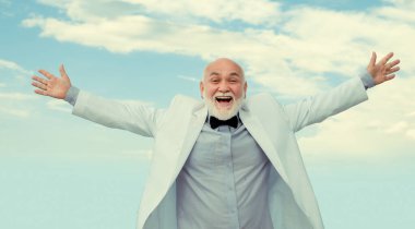 Başarılı eski moda kazananı, son sınıf yetişkin adam. Beyaz takım elbiseli başarılı erkek eğleniyor.