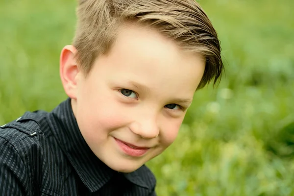 スタイリッシュな黒のTシャツを着た笑顔の男の子屋外で草の背景 — ストック写真