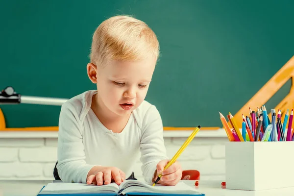 在黑板桌旁的教室里 可爱的小男孩 黑板复制空间 教育进程 — 图库照片