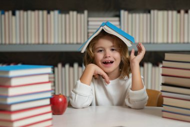 Okula dönelim. Öğrenci çocuk kütüphanede kitap okuyor. Çocuk gelişimi, okumayı öğrenmek. Öğrenci kütüphanede kitap okuyor. Ödev yapan okul çocuğu, sıkı çalış.