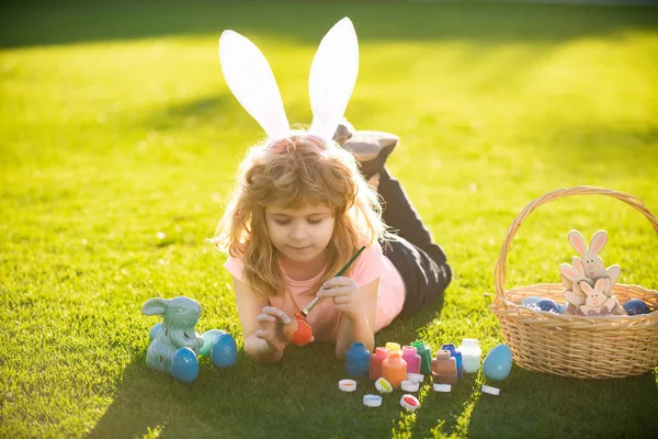 孩子们躺在公园的草地上吃着蛋 复活节兔子的孩子 兔子复活节耳朵里的小男孩在画蛋 — 图库照片