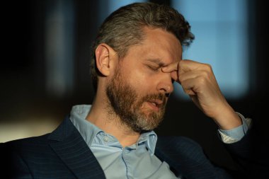 Yorgun adamın korkunç bir baş ağrısı var. Bitkin, sağlıksız hisseden, baş ağrısı hastalığına üzülen bir adam. Stresli orta yaşlı bir adamın baş ağrısı olan portresi. Migren ve baş ağrısı konsepti