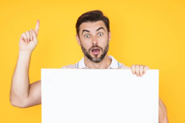 Stüdyo arkaplanındaki boş tahtada işaret parmağı tutan bir adam görülüyor. Kopyalama uzayı olan boş tabela. Reklam konsepti. Kopyalama alanı olan reklam panosu, boş model