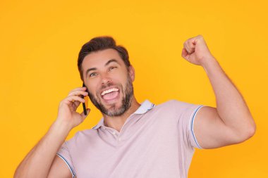 Akıllı telefon kullanan, sohbet eden, sosyal medyada yazı yazan heyecanlı bir adam. Telefondaki adam stüdyonun arka planında izole edilmiş. Blog yazarı telefonda konuşuyor