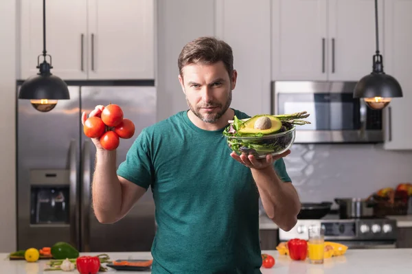 stock image Handsome man cooking salad in kitchen. Guy cooking on kitchen with vegetables. Portrait of casual man cooking in the kitchen with vegetable ingredients. Casual man cooking salad at home in kitchen