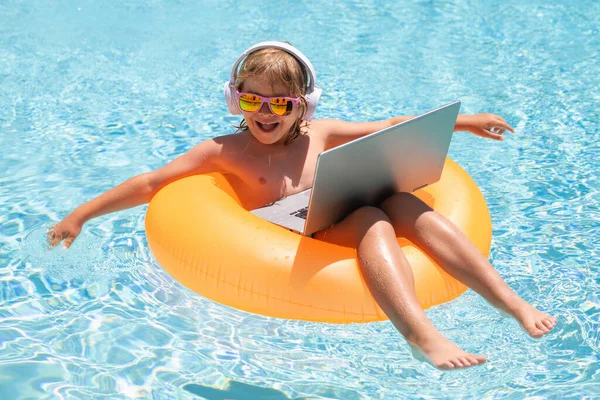 Kids working with laptop on summer vacation holidays. Little freelancer using computer, remote working in pool