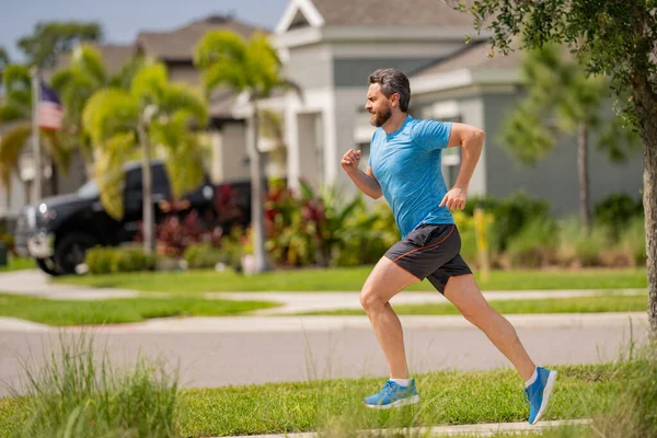 近所の通りを走っている男 通りを走っているハンサムなアスリート スポーツウェアランニング 都市トレーニングで男の完全な長さのショット — ストック写真