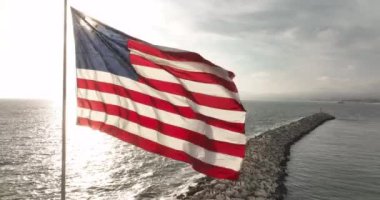 Amerika Birleşik Devletleri bayrağı, deniz ya da okyanus yakınlarında rüzgârda dalgalanıyor.