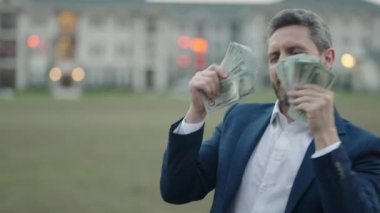Dışarıda nakit para tutan bir adam var. Bir sürü banknotu olan bir iş adamı portresi. Dolar parası konsepti. Kariyer zenginliği işi. Nakit dolar afişi