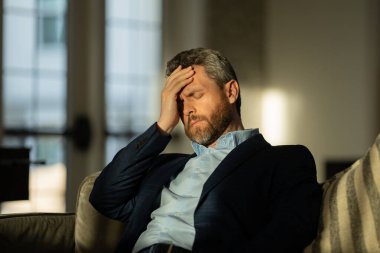 Yorgun adam acı çekiyor. Stresli bir adamın portresi ofiste baş ağrısından muzdarip. Stresli bir iş. Ağrılı bir adamın ağrıdan dolayı migreni tutar. Stresli, baş ağrısından yorgun bir adam.