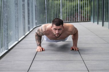 Spor salonunda poz veren kaslı iri kıyım. Spor aletlerinin yanında fitness mankeni. Genç kaslı adam egzersizi. Spor salonundaki güçlü kaslı adam. Spor ve motivasyon. Ağırlıkla egzersiz yapar