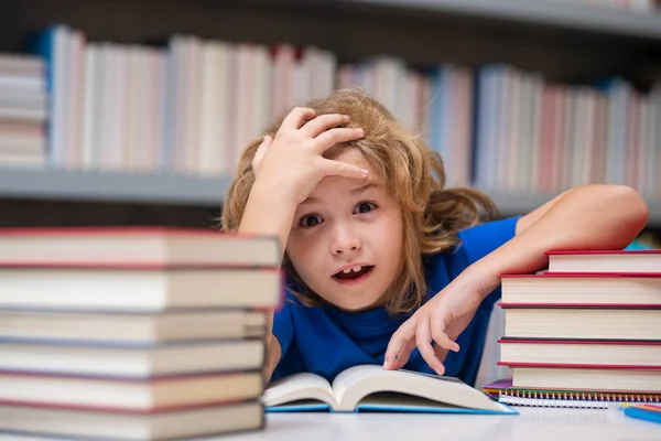 stock image Nerd pupil. School child pupil reading book at school. Kid doing homework, sitting at table by books, in classroom