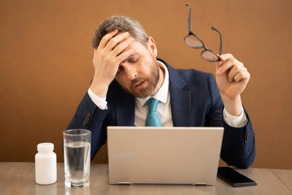 Tired, headache and eye strain on laptop. Man with stress, burnout and fatigue eyestrain. Business man rubbing tired eyes after computer work. Vision problem, bad sight feeling eyestrain fatigue pain