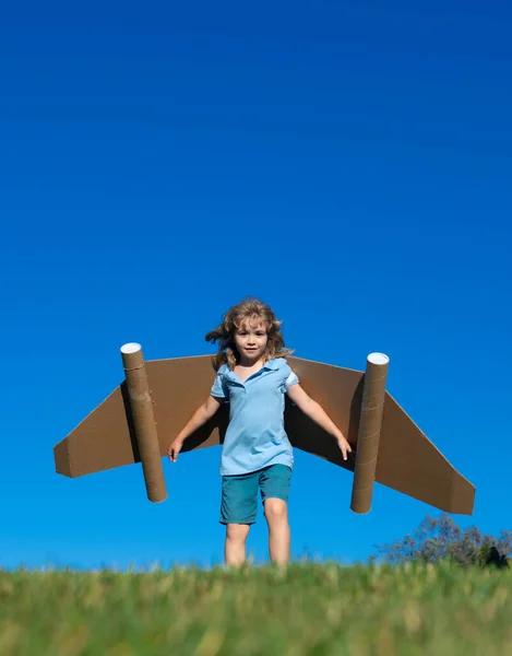 小さな子供は宇宙飛行士やパイロットを演じる 青空を背景に子供 紙の翼ジェットパックの夢を持つ子供たち 子供たちは飛ぶ夢を想像する おもちゃのジェットパックと面白い子供 — ストック写真