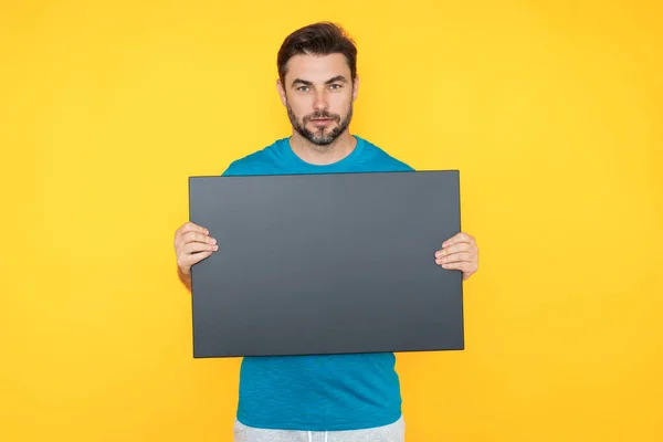 Information concept. Man with blank placard. Demonstrating copy space for your text or design. Man showing empty advertisement board on studio background. Blank placard with copy space, signboard