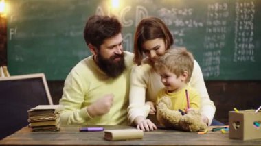 İlkokuldan bir çocuk. Genç anne baba ve küçük anaokulu çocuğu birlikte oturur, resim çizer, oynar, deftere resimler çizer, erken gelişim