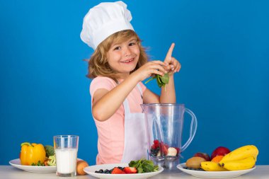 Aşçı önlüğü giymiş çocuk aşçı ve stüdyo arka planında izole edilmiş şef şapkası. Sağlıklı beslenme çocuklar için.
