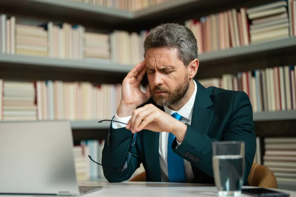 千禧年商人在办公室头疼 穿着西服在总公司笔记本电脑上工作的商人摘下眼镜时 会患上偏头痛或偏头痛 头疼得精疲力竭的人 — 图库照片
