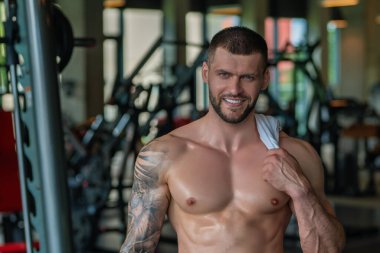 Fit guy doing exercise at gym. Handsome sporty man workout with with dumbbells on gym. Male athlete with dumbbell on fitness workout. Fitness man in gym. Muscular sportsman workout with weight in gym