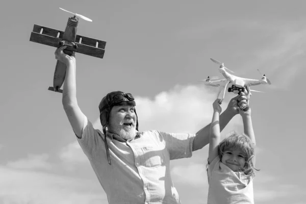 Child boy and grandfather playing with toy plane and quadcopter drone against sky. Child pilot aviator with plane dreams of traveling