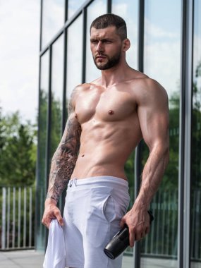 Spor salonunda poz veren kaslı iri kıyım. Spor aletlerinin yanında fitness mankeni. Genç kaslı adam egzersizi. Spor salonundaki güçlü kaslı adam. Spor ve motivasyon. Ağırlıkla egzersiz yapar