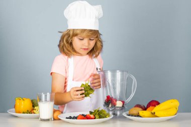 Aşçı önlüğü giymiş çocuk aşçı ve stüdyo arka planında izole edilmiş şef şapkası. Sağlıklı beslenme çocuklar için.