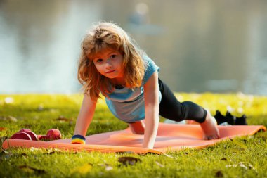 Çocuk bahar parkında şınav çekiyor. Sağlıklı aktiviteler, çocuk yaşam tarzı. Parkta egzersiz yapan güçlü bir çocuk. Spor portresi çocuklar. Çocuk yukarı itiyor. Spor çocukları.