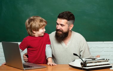 Okula geri ve eğitim konsepti. Sınıfta ilkokul öğretmeni ve öğrencisi. Boşluk Kopyala. Öğretmenler sınıfta masalarda okuyan öğrencilere yardımcı olur. Baba öğretmen