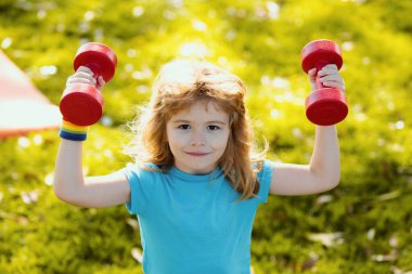Sağlıklı çocuk hayatı ve spor anlayışı. Çocuk portresi dışarıda halterlerle çalışıyor. Çocuklar için motivasyon ve spor kavramı