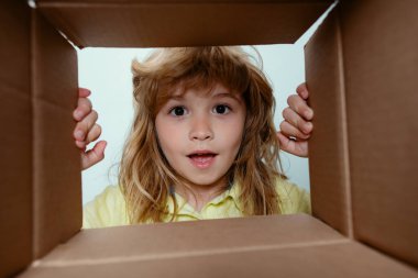 7 yaşındaki süpriz çocuk bavulunu açtı, kutusunu açtı ve içine baktı. Paket, teslimat, sürpriz, çocuk için hediye. Çocuk duyguları ve çocuk yüz ifadeleri