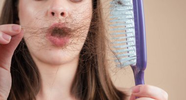 Saç dökülmesi. Kadın saç dökülmesinden rahatsız. Sorunlu saçlı, izole edilmiş üzgün bir kızın portresi. Endişeli kız uzun hasarlı, sağlıksız saçları elinde tutuyor.