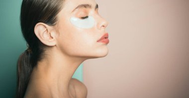 Derisinin icabına bakıyorum. Kadın göz yamaları kullanarak evde zaman geçiriyor. Günlük şımartıcı rutin. Makyaj yapmak yerine ilk bakım. Modern kozmetik. Göz yamaları kavramı. Nemlendirme göz yamaları.