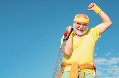 Kıdemli adam mavi gökyüzünde egzersiz yapıyor. Sağlıklı yaşlı bir sporcunun portresi. Son sınıf öğrencisi fitness eğitimi alıyor. Sportif. En iyi kardiyo çalışması