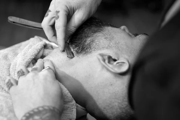 Hair Stylist and Barber. Hairdressers work for a handsome guy at the barber shop. Barber scissors and straight razor barber shop. Male client getting haircut by hairdresser