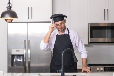 Yemek pişirme ve aşçılık konsepti. Mutfakta üniformalı aşçı. Erkek aşçı ya da önlüklü aşçı. Aşçının bereli portresi. Yemek pişirme konsepti