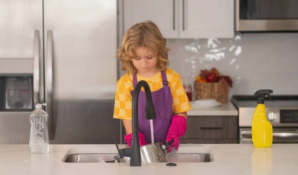 洗浄と洗浄の概念 子供は台所で皿を洗うのを助ける 台所の子供の掃除 家事に役立ちます 子供の男の子家政婦台所で掃除する子供 — ストック写真