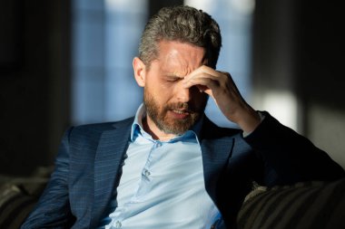 Baş ağrısı çeken yorgun bir adam. Başa dokunmak, ağrıyı dindirmek, migren. İş sorunları. İflas, mali sorun ve kriz konsepti. Bin yıllık İspanyol adamın başı ağrıyor. Migren.