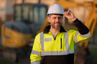 İnşaat alanında çalışan bir işçi. Şapkalı bir inşaatçı. Kasklı bir inşaat işçisi. Miğferli inşaat işçisi. İnşaat binasında sanayi işçisi. İnşaatçı, kazıcıyla birlikte inşaat alanında.