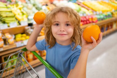Alışveriş, indirim, satış konsepti. Alışveriş sepetli çocuk. Dükkandaki çocuk. Süpermarket ve market konsepti. Süpermarketten ürün alan küçük çocuk müşteriler