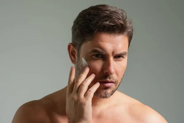 Man care of skin. Charming man with perfect soft skin. Male beauty and skincare concept. Man cosmetic, skin treatment. Morning hygiene. Mens cosmetics and wellness. Skincare. Man with cream on face