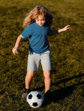 Futbolcu çocuk futbol oynuyor. Çocuk dışarıda futbol oynuyordu. Çocuklar futbol maçında gol attılar. Çocuk çimlerin üzerinde futbol topunu tekmeliyor.
