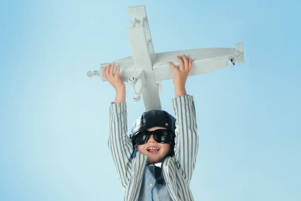 Child pilot with toy airplane dreams of traveling in summer in nature. Kids dreams. Child plays with a toy plane and dreams of becoming a pilot