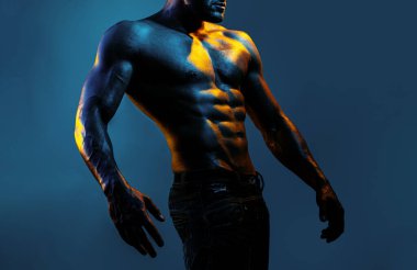 Güçlü vücutlu çıplak bir sporcu. Gövde Adam. Mavi neon arka planda poz veren kaslı, üstsüz seksi bir adamın portresi.